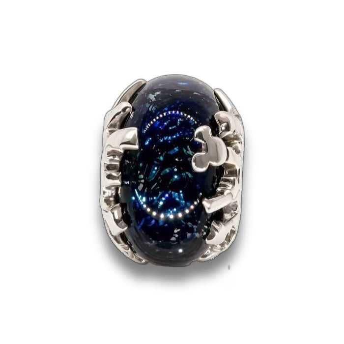A silver-toned ring featuring an oval dark blue glass charm with a starry galaxy pattern, set against a clean white background with a soft reflection.