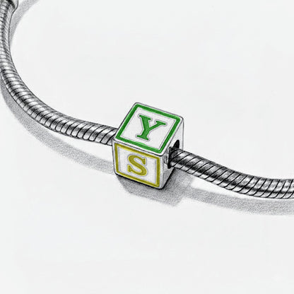 Bracelet with a charm shaped like a green and white block with 'YES' on it.